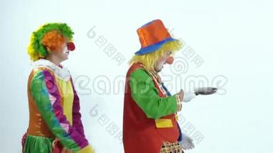 两个马戏团小丑扔出一个玩具煎饼，然后用煎锅把它抓起来
